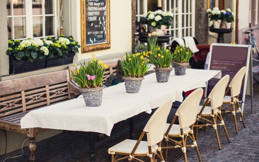 Сozy outdoor cafe in Europe with white tablecloth and flower ba